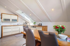 A modern kitchen with a skylight, wooden cabinets, and a dining area with a table and chairs.