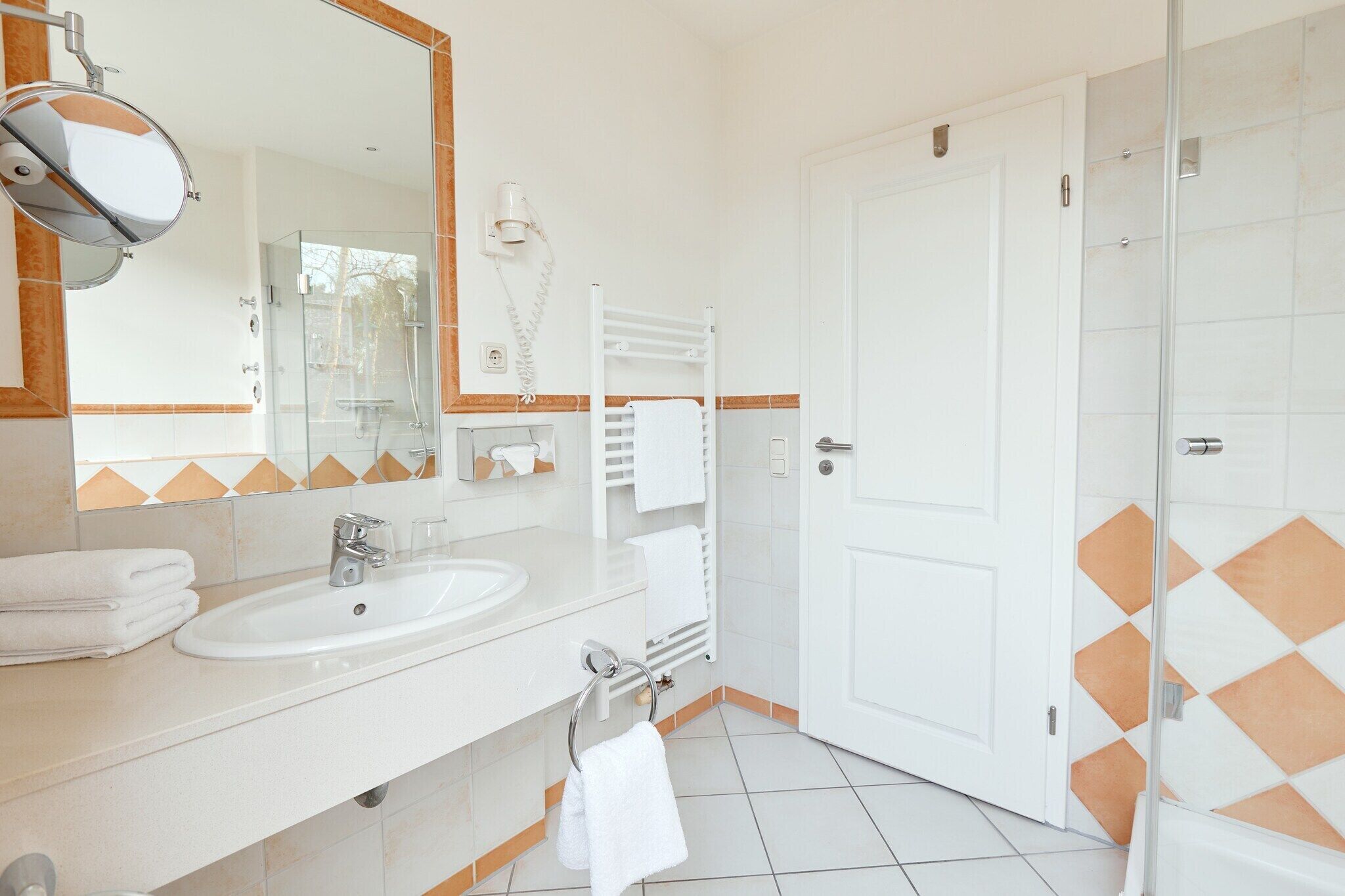 Een moderne badkamer met een wit wastafelmeubel, spiegel en handdoekhouder.