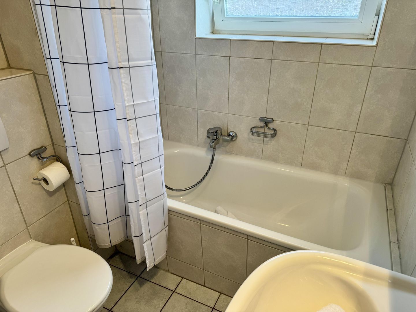 Un baño con bañera, inodoro y cortina de ducha.