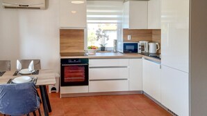A modern kitchen with white cabinets, a built-in oven, a microwave, and a coffee maker. - 2 bedroom awesome apartment in Vir (Vir)