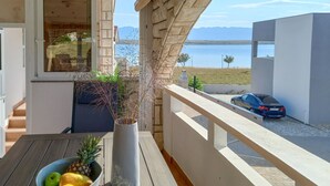 A balcony with a view of a lake and mountains, a car parked outside, and a table with a fruit bowl. - 2 bedroom awesome apartment in Vir (Vir)