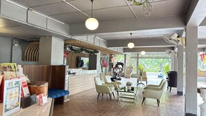 A modern indoor space with a reception desk, seating area, and a view through large windows. - Standard Twin Charm | Great for Friends (Chiang Mai)