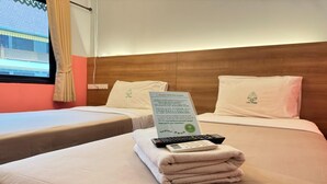 A hotel room with two beds, a sign with text, a remote control, and a folded towel. - Standard Twin Charm | Great for Friends (Chiang Mai)