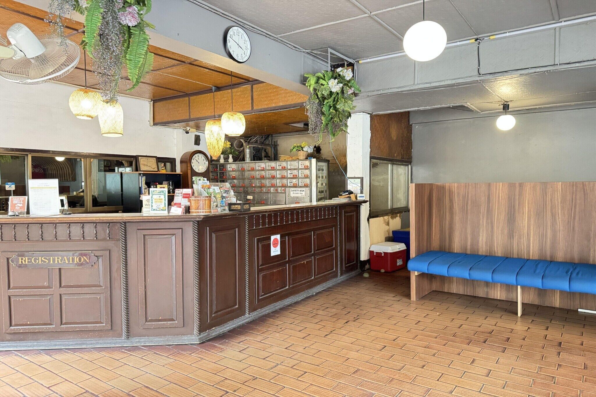 Een receptiegedeelte met een receptiebalie, een klok en een zithoek met een blauwe bank.