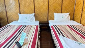 A room with two beds, each with a striped bedspread and white pillows. A remote control and a sign are visible on the bed. - Spacious Superior Twin | Lounge in Comfort (Chiang Mai)