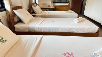 Een hotelkamer met twee eenpersoonsbedden, elk met een houten hoofdbord en witte lakens.
