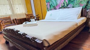A large bed with a wooden frame and intricate carvings, a white bedspread, and a pillow with a logo. - Relaxed Superior Double | Unwind in Style (Chiang Mai)