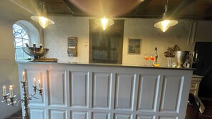 Une cuisine avec un comptoir-bar blanc, des luminaires suspendus, une fenêtre offrant une belle vue et un sol en briques.
