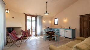 A cozy living room with a fireplace, a dining area, and a kitchen with a blue countertop. - Casa Gialla (Gavorrano)
