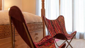 A bedroom with a bed, a wooden nightstand, and a colorful woven chair. - Casa Gialla (Gavorrano)