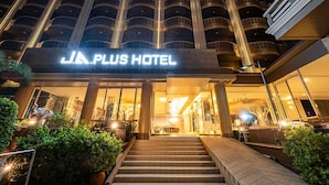 The exterior of J.A. PLUS HOTEL with a grand entrance, multiple balconies, and a well-lit facade.