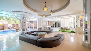 A spacious lobby with a curved seating area, a pool, and large windows.