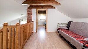 Un dormitorio tipo loft con escalera de madera, pared de ladrillo, ventana con cortinas, un sofá y un radiador.