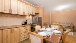 A compact kitchen with wooden cabinets, a gas stove, and a refrigerator. There is a dining table set with plates, glasses, and cutlery. - Cozy apartment in Vrbovsko with sauna (Vrbovsko)