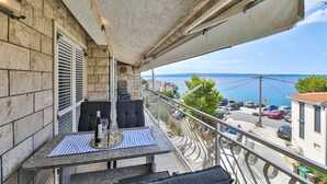 A balcony with a table set for two, overlooking a parking area and a body of water.