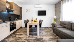 A modern kitchen with a dining area, a flat-screen TV, and a grey sofa. - Beautiful apartment in Sibenik (Sibenik)