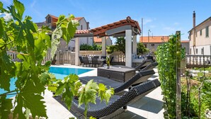 A pool area with lounge chairs and a pergola. - Beautiful apartment in Sibenik (Sibenik)