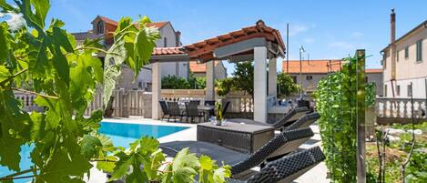 A pool area with lounge chairs and a pergola.