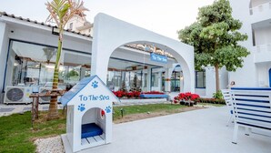 Hotel que admite mascotas, con una caseta para perros que dice 'Al Mar' y un cartel sobre la entrada.