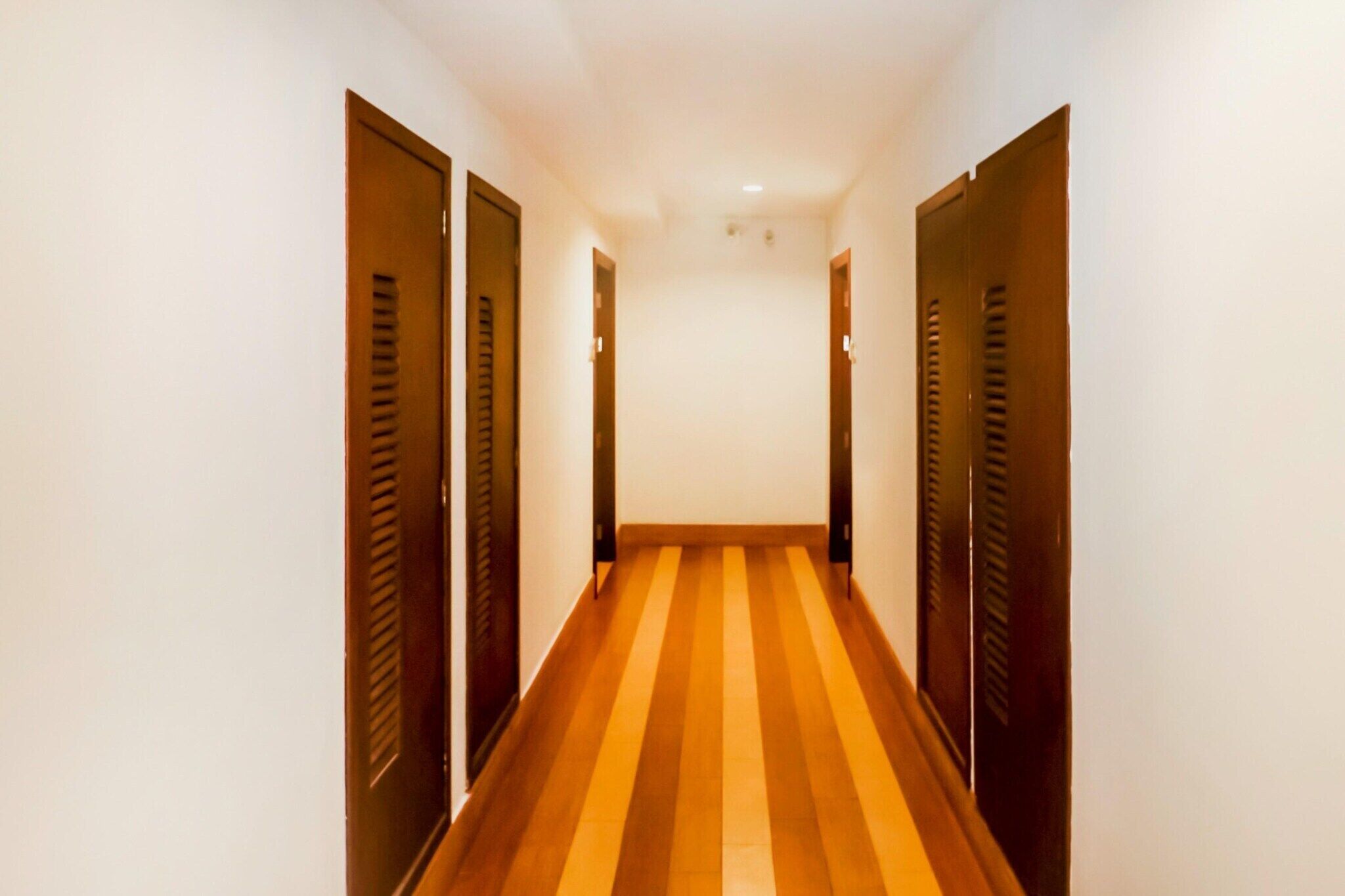 A narrow hallway with wooden doors on both sides and a striped floor.