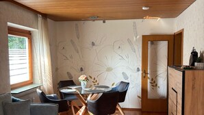 Una habitación acogedora con techo de madera, una mesa de comedor con sillas, un sofá y un aparador.
