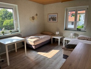 Une chambre à coucher avec un lit, des tables de chevet, un radiateur, une fenêtre donnant sur un paysage agréable et un tableau accroché au mur.
