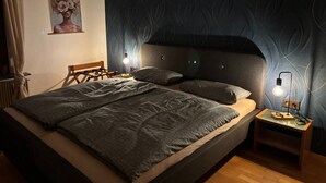 Un dormitorio moderno con una cama grande, un cabecero, lámparas de noche y un cartel en la pared.