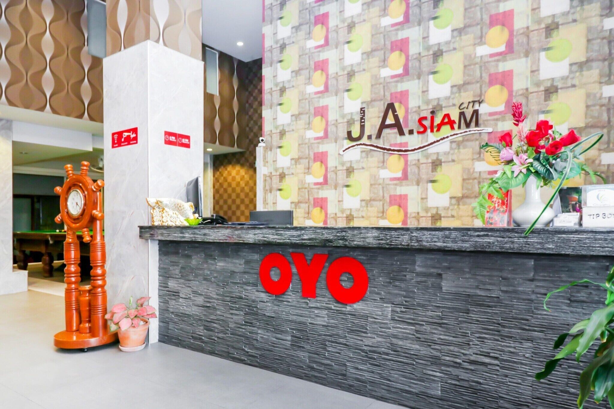 A reception desk with a clock, a flower vase, and the name "OYO" prominently displayed.