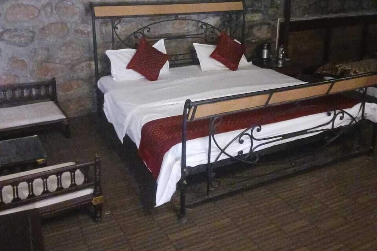 A bedroom with a stone wall, a wooden bed frame, and a metal headboard.