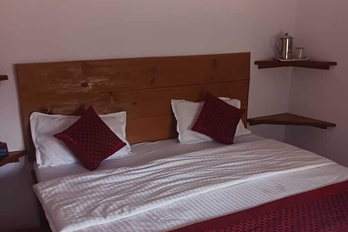 A bed with a wooden headboard, two pillows, and a red blanket.