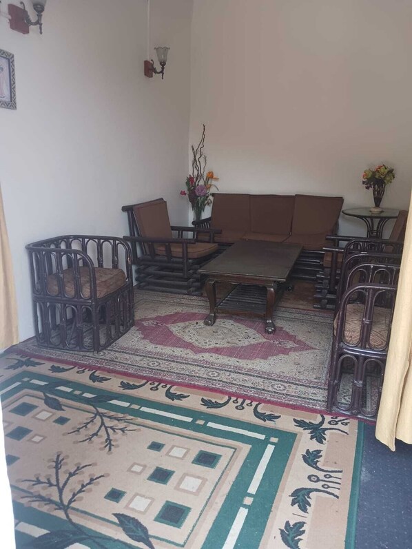 A living room with a sofa set, a coffee table, and two chairs. There is a patterned rug on the floor.
