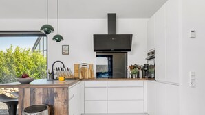 A modern kitchen with a large island, a built-in oven, and a black range hood. - "Merve" - 250m from the sea by Interhome (Odder)