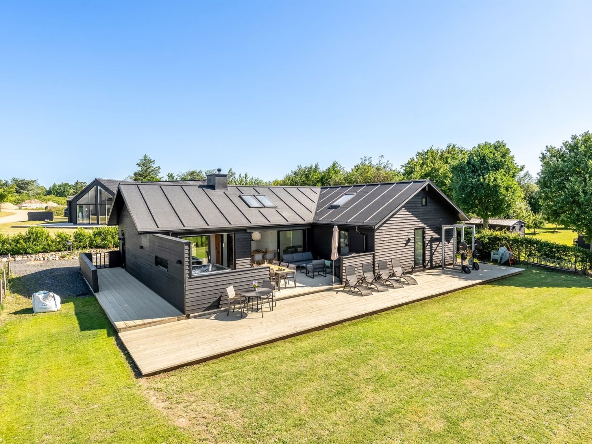 A modern house with a large deck, a hot tub, and a covered outdoor seating area.