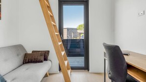 A modern room with a sofa, a desk, and a wooden ladder leaning against the wall. - "Merve" - 250m from the sea by Interhome (Odder)