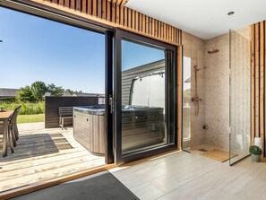 Un baño moderno con cabina de ducha de vidrio, un jacuzzi y una terraza amueblada al aire libre.