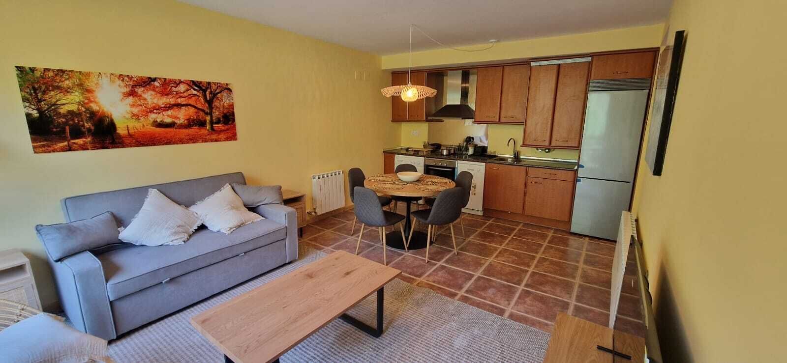 Un espace de vie compact comprenant un canapé, une table à manger et un coin cuisine avec un réfrigérateur et des placards.