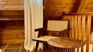 A wooden cabin interior with a round table, two chairs, a window with curtains, and a view of greenery outside. - Apartamentos Snö Escarrilla (Sallent de Gallego)