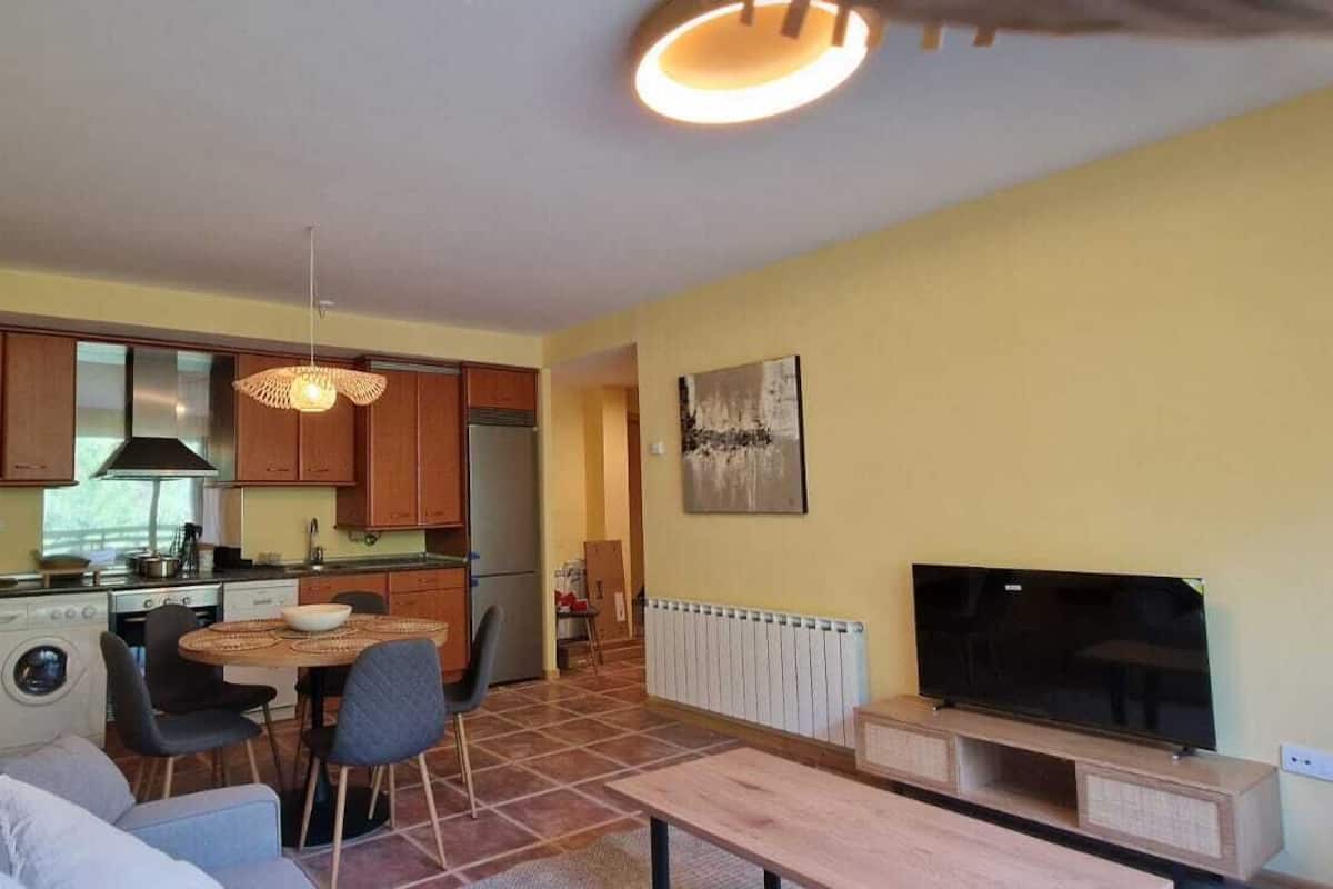 Un espacio habitable compacto con kitchenette, comedor, sofá y televisor.
