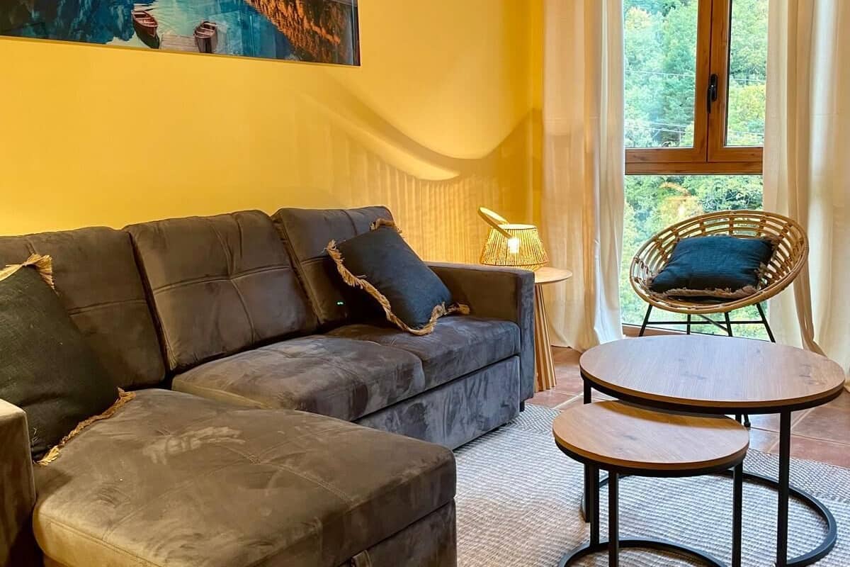 Una sala de estar con un sofá, una mesita, un sillón de mimbre y un cuadro en la pared.