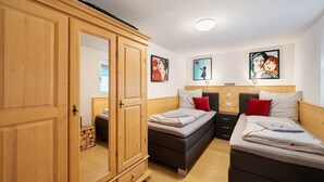Una habitación con dos camas, un armario de madera y obras de arte en las paredes.