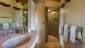 A bathroom with a stone sink, a mirror, a shower with mosaic tiles, and a towel rack. - Oak (Gavorrano)