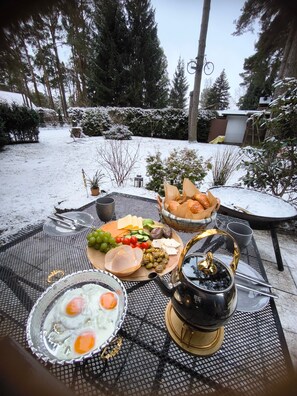 Una mesa al aire libre con comida y una bebida caliente.