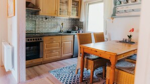 Eine kleine Küche mit Holdekor-Schränken, einem eingebauten Backofen und einem Essbereich mit Tisch und Stühlen.