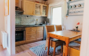 A compact kitchen with wooden cabinets, a built-in oven, and a dining area with a table and chairs.