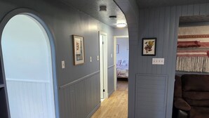A narrow hallway with wooden flooring, a blue wall, and a door leading to another room. - The Tidehouse, Relax with the whole family at this peaceful place to stay. (Laurenceton)