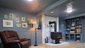 A cozy living room with a fireplace, wooden flooring, and a blue accent wall. - The Tidehouse, Relax with the whole family at this peaceful place to stay. (Laurenceton)