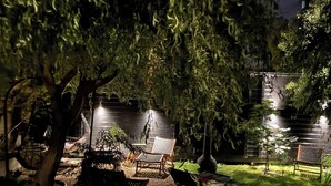 A garden area with a bench, a table, and a chair under a tree.