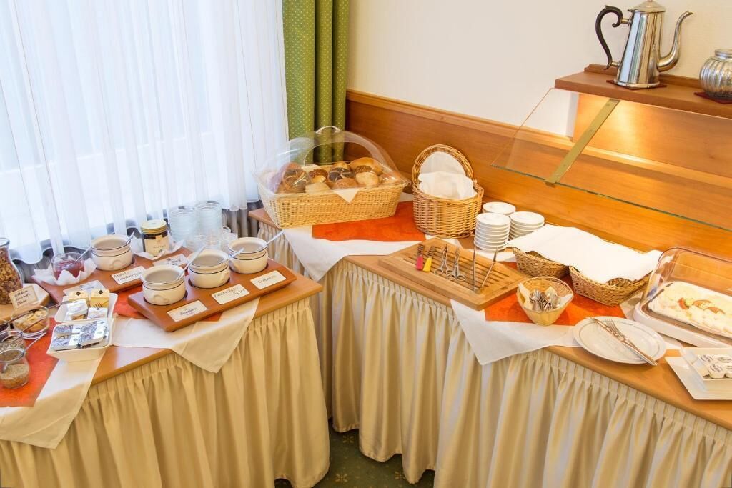 Un buffet de desayuno con diversos alimentos, bandejas de servicio y utensilios.