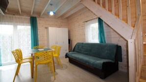 Ein Interieur einer Holzhütte mit Essbereich, einer Couch und einer Treppe.