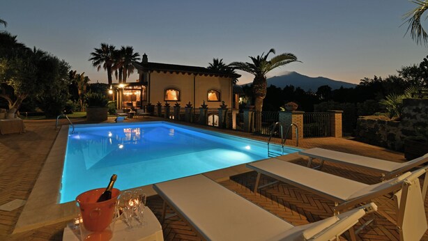 An outdoor swimming pool with lounge chairs and a table with a bottle and glasses. - VILLA BIDDIZZA an oasis of peace and relaxation (Sicilia)